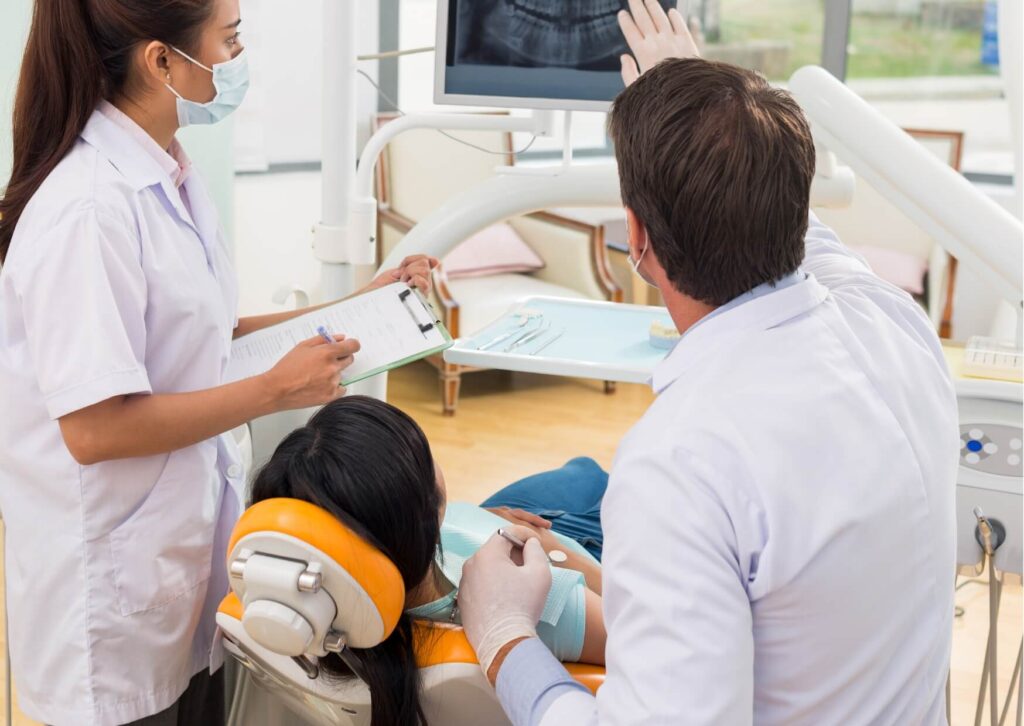 Dentist reviewing a dental X-ray with a patient to identify what a cavity looks like and determine the appropriate treatment.