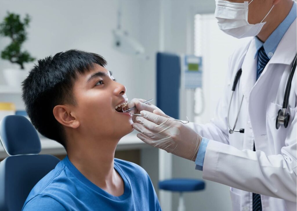 Dentist examining a patient's back teeth to evaluate what a wisdom tooth coming in looks like during a routine dental exam.
