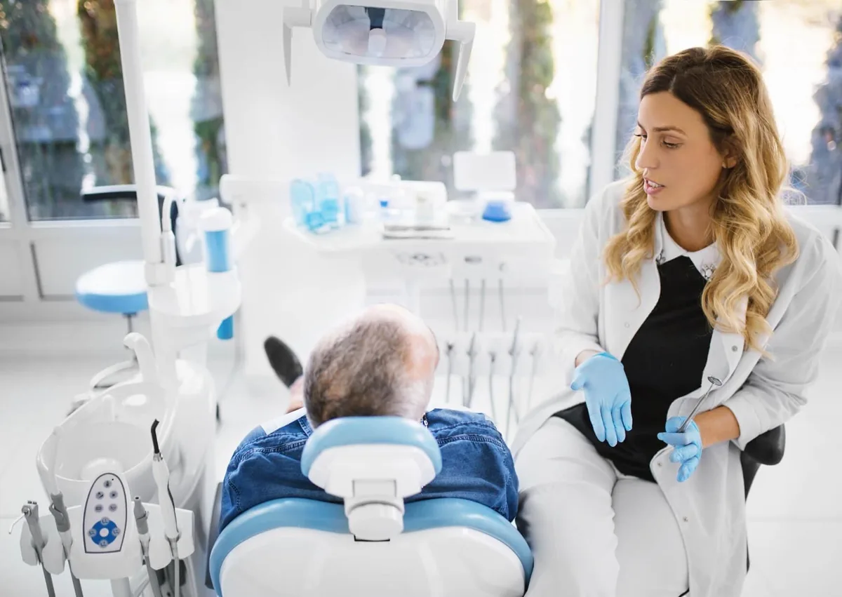Dentist discussing obstructive sleep apnea treatment options with an older patient during a dental consultation.