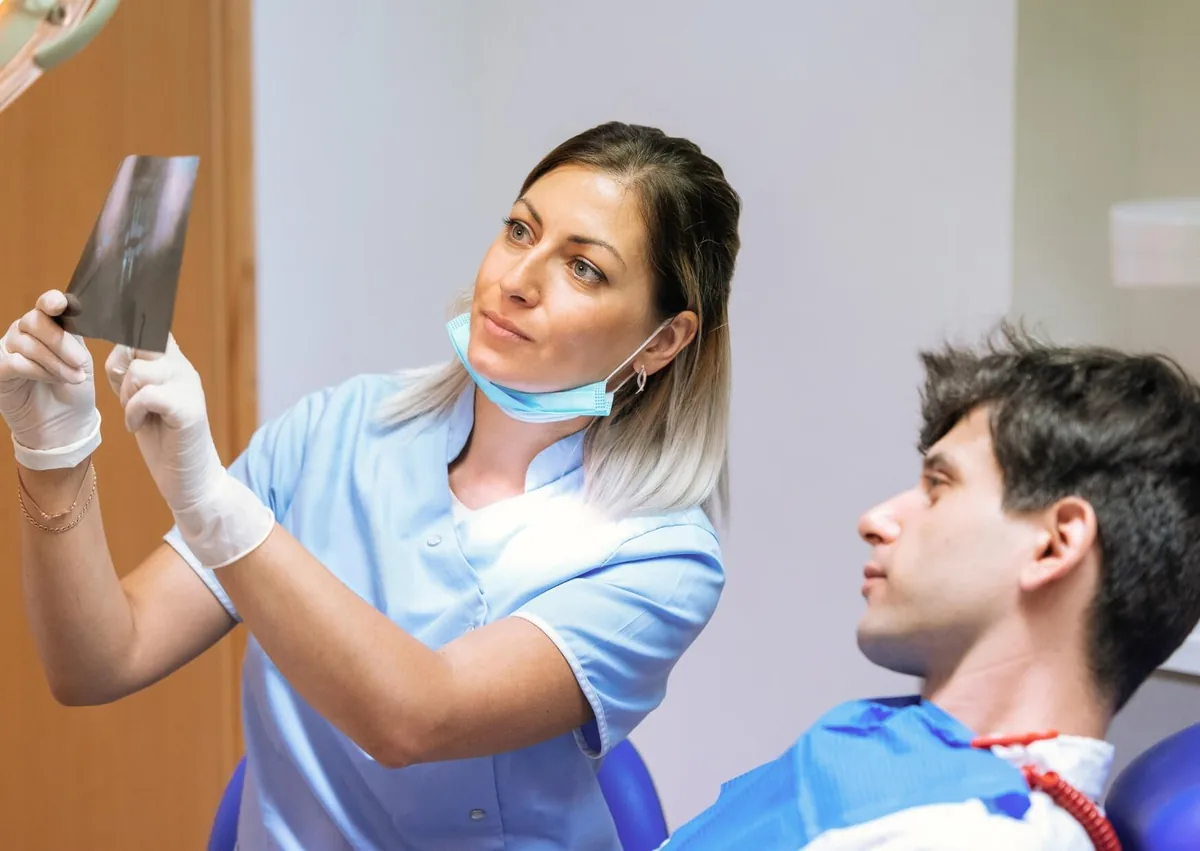 Dentist reviewing a dental X-ray with a patient during a consultation to assess treatment options and costs for affordable dental implants.