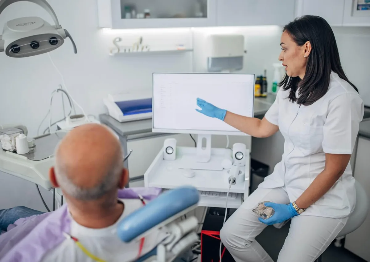Dentist discussing full mouth dental implants cost and treatment planning with a patient during a consultation at a dental clinic.